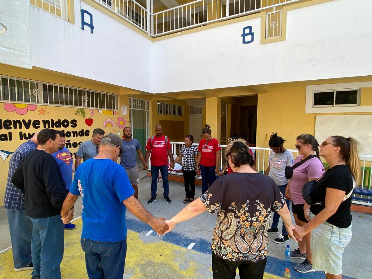 Equipo misionero y voluntarios orando tomados de la mano